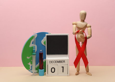 Wooden puppet with Red awareness ribbon and calendar with date December 01, globe, blood test tube...