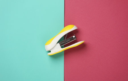Yellow Stapler on pink blue background. Top viewの写真素材
