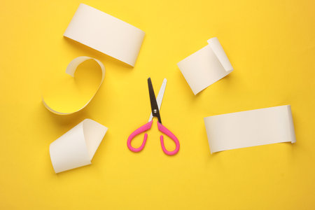 Scissors and paper tapes on yellow backgroundの写真素材