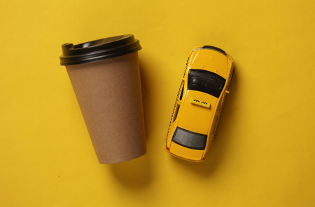 Toy taxi car model with coffee cup on yellow background. Top viewの写真素材