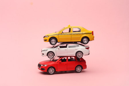 Stack of toy cars on pink background. Auto service concept