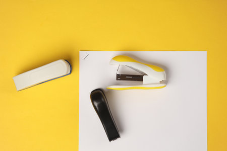 Staplers with sheets of paper on a yellow background. Business conceptの写真素材