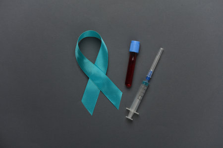 Blue ribbon symbolizing support of men and blood test tube on dark background. Blue november...