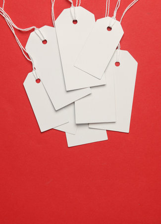 Blank white tags with ropes on red background. Mock up, Template for design. Copy space. Sale, shopping conceptの写真素材