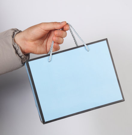 Man's hand in down jacket holding paper bagの写真素材