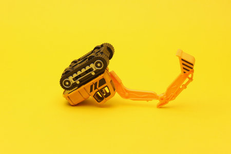 Toy excavator on yellow backgroundの写真素材