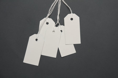 Blank white tags with ropes on dark gray background. Mock up, Template for design. Copy space. Sale,...
