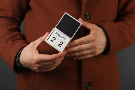 Man in woolen coat holds calendar with the date February 22の写真素材