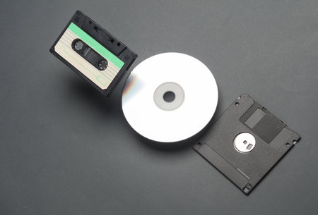 Retro storage media. Audio cassette, CD and floppy disk on a dark backgroundの写真素材
