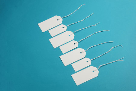 Set of blank white tags with ropes on blue background. Mock up, Template for design. Copy space....