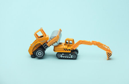 Toy asphalt paver and excavator on blue backgroundの写真素材