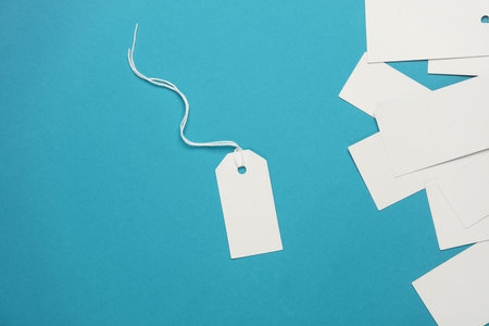 Set of blank white tags with ropes on blue background. Mock up, Template for design. Copy space....
