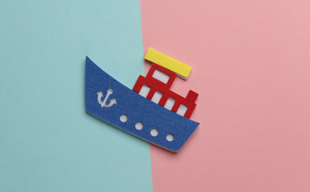 Toy ship made of felt on pink blue background. Travel concept