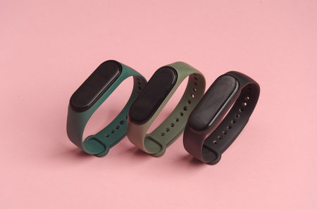 Three smart bracelets on a pink background