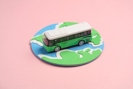 Toy bus miniature and globe on a pink background.Travel concept