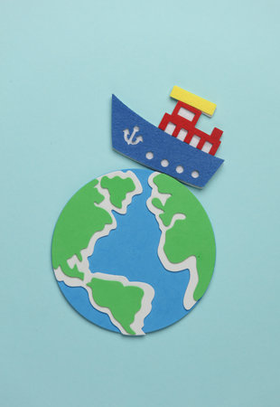 Toy ship made of felt and globe on blue background. Travel concept