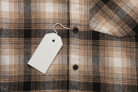Checkered shirt with white blank tag on a string. Shopping, sale concept. Template for design