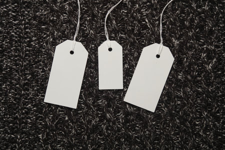 Three white empty tags with a string on a sweaterの写真素材
