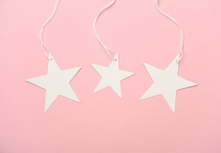 White tags on string in the shape of stars on pink background