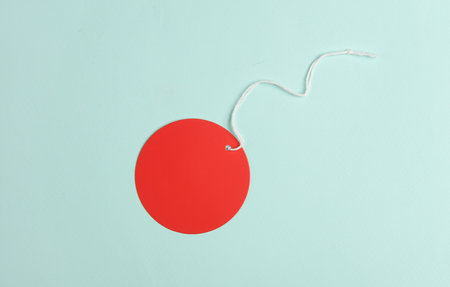 Red blank round tag with string on blue backgroundの写真素材