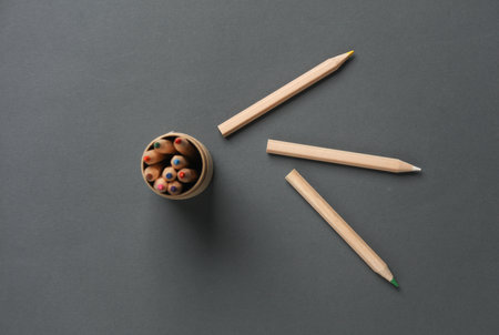 Box with wooden colored pencils on dark gray background. Creativity, art. Top viewの写真素材