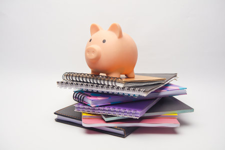 Piggy bank with Stack of different notepads on white backgroundの写真素材
