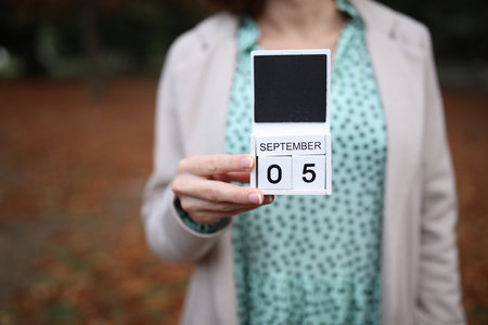 Woman holds calendar with the date September 5 outdoors.の写真素材