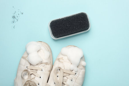 White sneakers with cleaning foam and brush on a blue background. Shoe careの写真素材