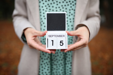 Woman holds calendar with the date September 15 outdoors.の写真素材