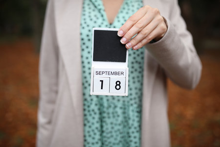 Woman holds calendar with the date September 18 outdoors.の写真素材
