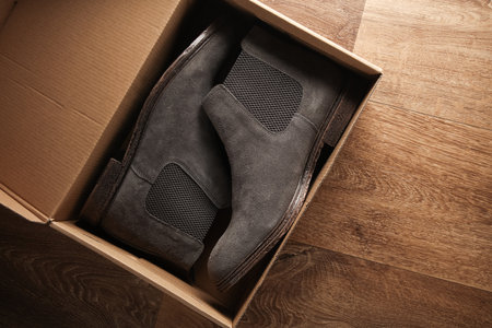 New pair of Chelsea shoes with box on the floor. Top view
