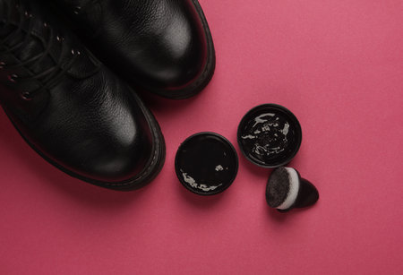 Leather boots and black shoe polish on pink background