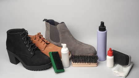 Men's and women's suede boots with accessories for shoe care on a white backgroundの写真素材