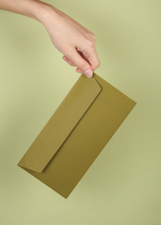 Hand holding envelope on green backgroundの写真素材