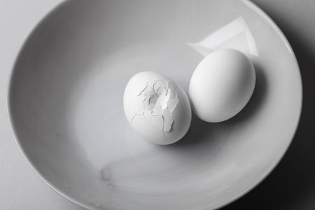 Whole and broken chicken eggs on plate