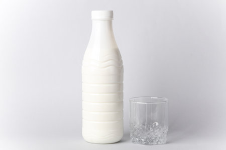 Plastic yogurt bottle with glass on gray backgroundの写真素材