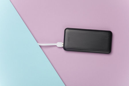 Power bank with cable on purple blue pastel backgroundの写真素材
