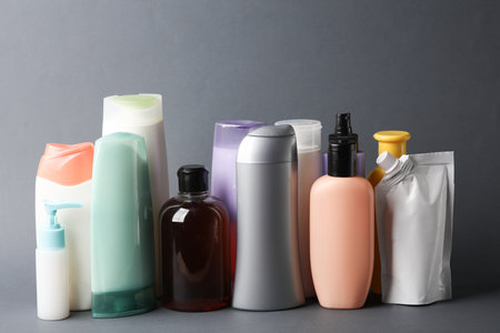 Different shampoo and other cosmetic product bottles on dark gray backgroundの写真素材