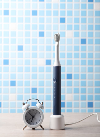 Modern smart ultrasonic toothbrush, alarm clock on the tableの写真素材