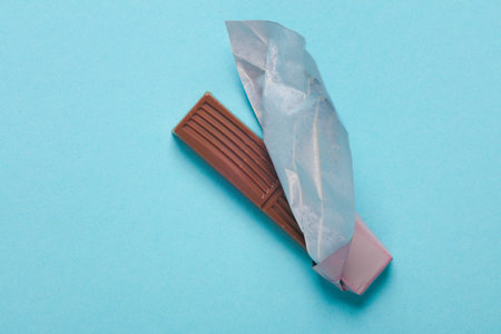 Opened chocolate bar with packaging on a blue backgroundの写真素材