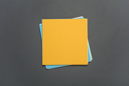 Square sheets of colored paper for origami creativity on dark gray background