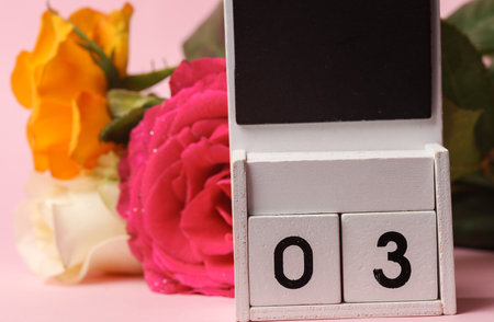 White Wooden calendar mockup with date 03 on pink background with flowersの写真素材