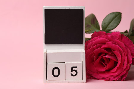 White Wooden calendar mockup with date 05 without month on pink background with flowersの写真素材