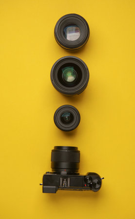 Professional modern mirrorless camera with set of lenses on yellow background. Top viewの写真素材