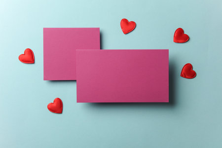 Blank business cards with red hearts on blue background. Top view.の写真素材