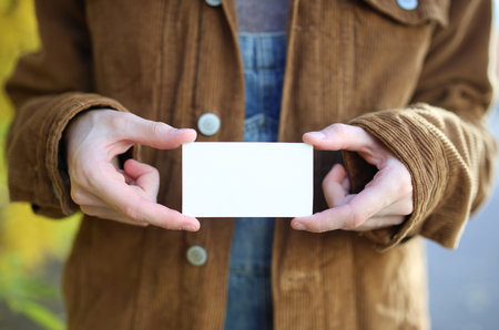 Hands holding business card against the background of autumn trees