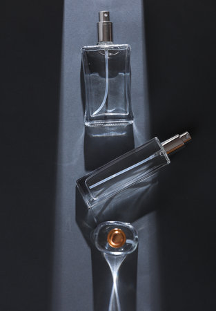 Perfume bottles on gray background with stripe of light and shadow. Minimalism. Beauty Concept photoの写真素材