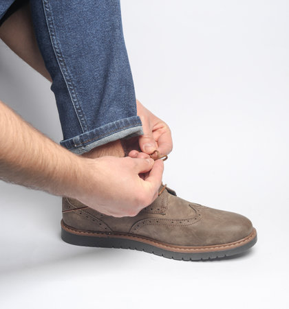 Man tying brogue shoe laces on white backgroundの写真素材