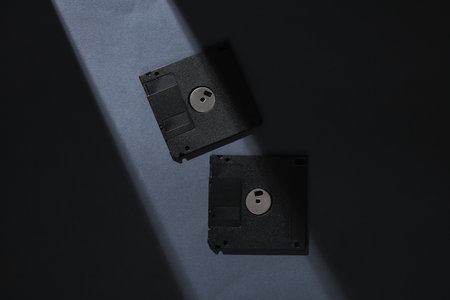 Retro floppy disks on a gray background with a stripe of light and shadow. Minimalism. Concept photoの写真素材