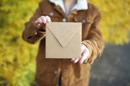 Woman holding craft envelope against the background of autumn trees